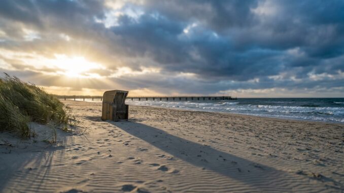 Leerer Sandstrand an der Ostsee im Herbst mit Strandkorb und Wolkenhimmel
