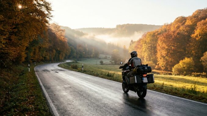 Motorradfahrer auf einer kurvigen Landstraße bei einer Motorradtour im Herbst